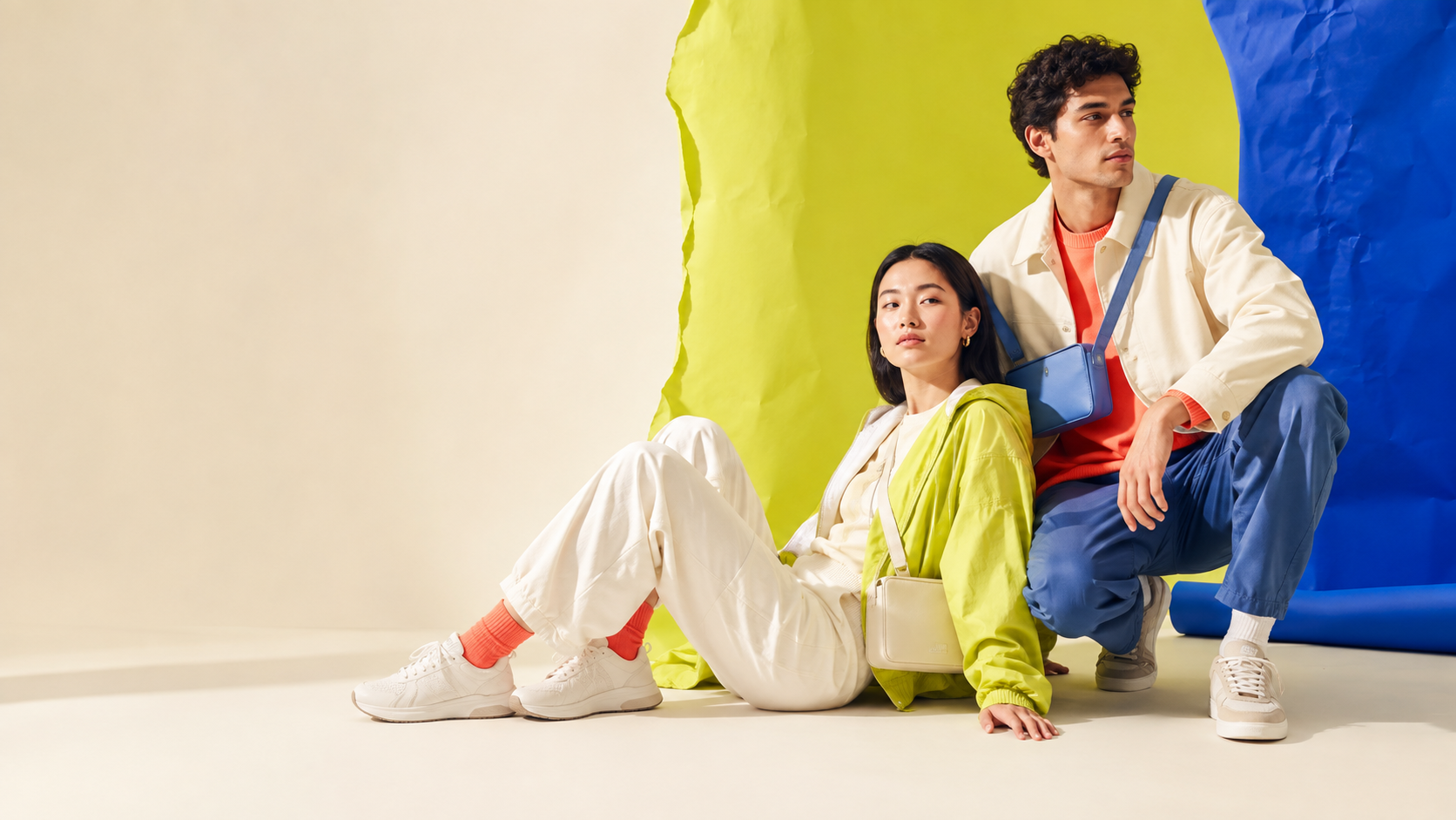 Two models in unbranded bright streetwear, sneakers and a crossbody bag